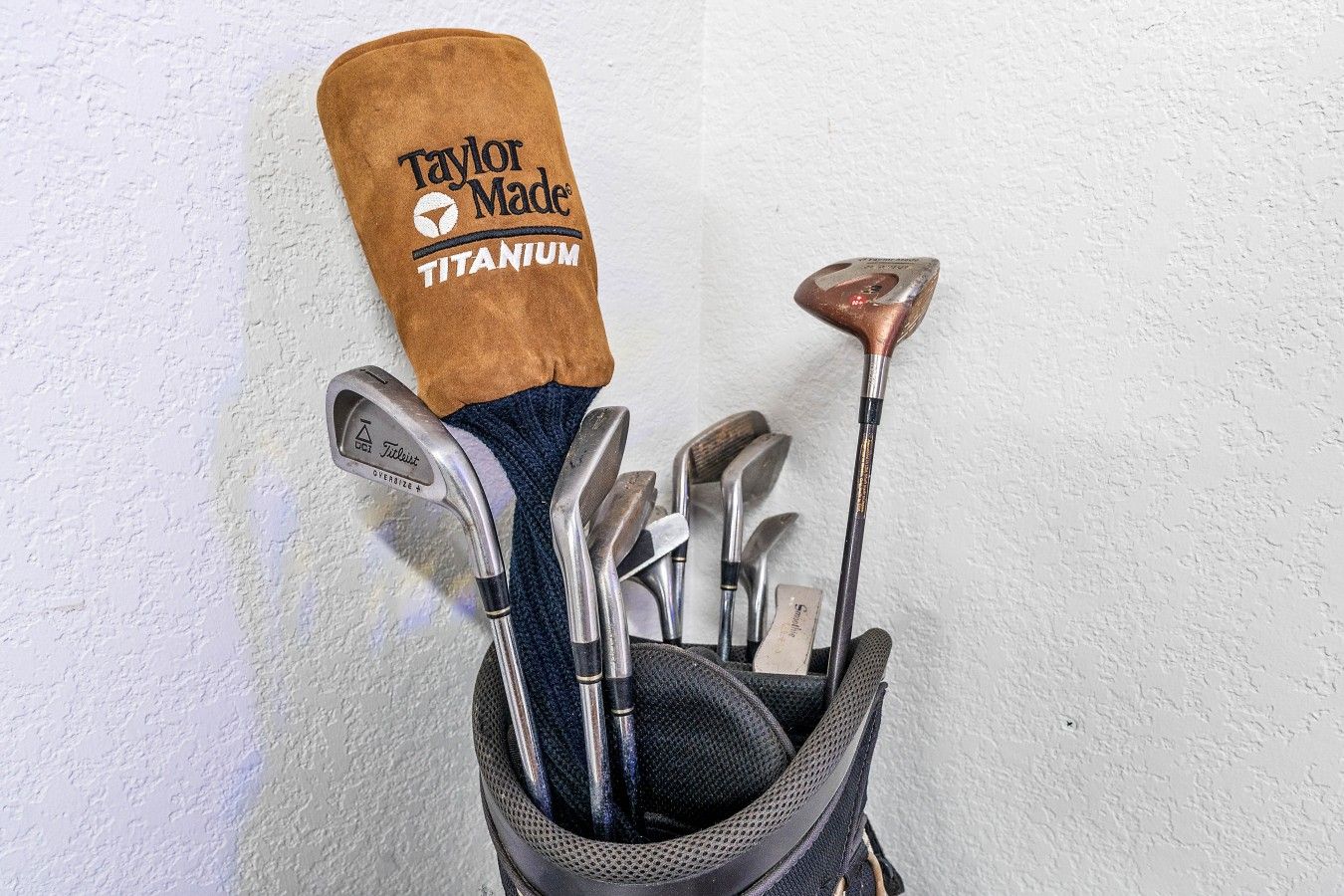 Bolsa de golf con una cubierta para la cabeza Taylor Made Titanium y varios palos de golf.