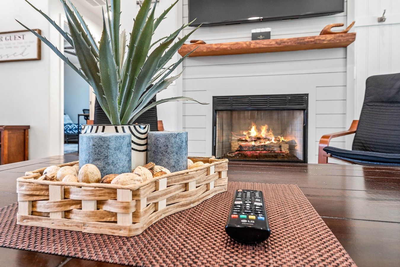 A living room with a fireplace, a television, a remote control, and a plant in a wooden crate.