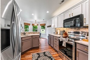 A modern kitchen with stainless steel appliances, a large island, and a view of the outdoors.