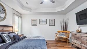 Un dormitorio con cama, una silla de madera, un aparador y decoración en la pared.