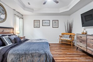 A bedroom with a bed, a wooden chair, a dresser, and wall art.