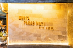 Een stenen muur met de tekst 'KERTA PARAS HATI CITY HOTEL' in gouden letters.