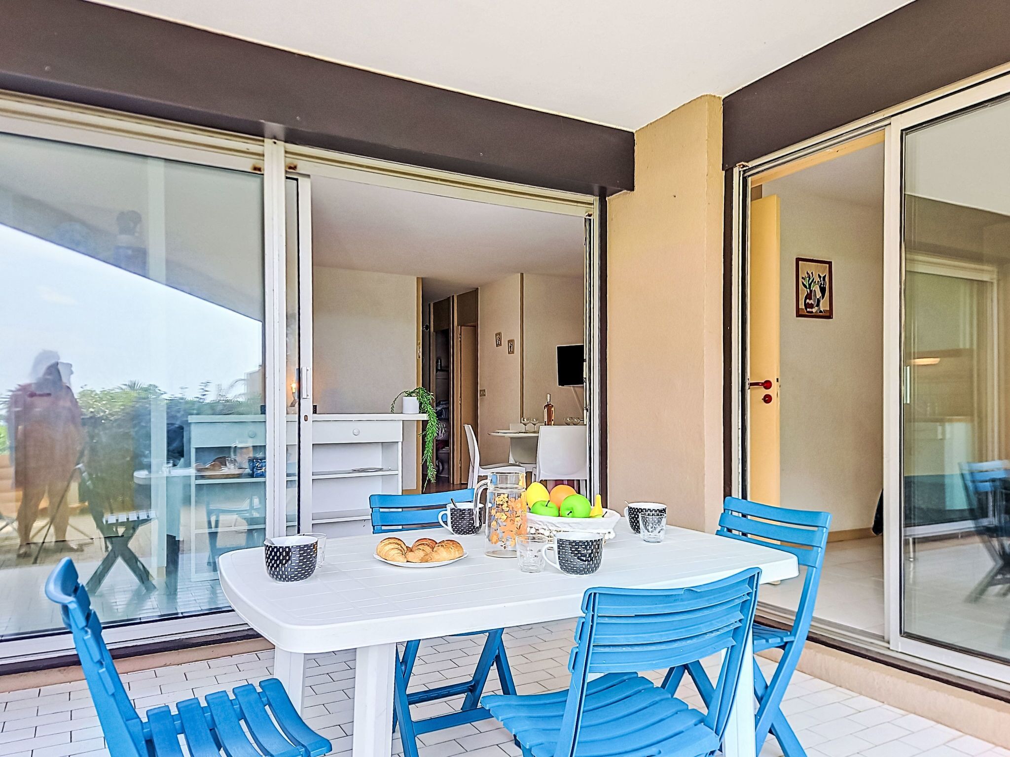 Een eethoek met een tafel en stoelen, een glazen deur die leidt naar een balkon, en een keuken die zichtbaar is door een open deur.