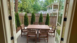 An open patio with a wooden table and chairs, surrounded by a wooden fence and trees. - King & Queen- All 5 Units (Auburn)