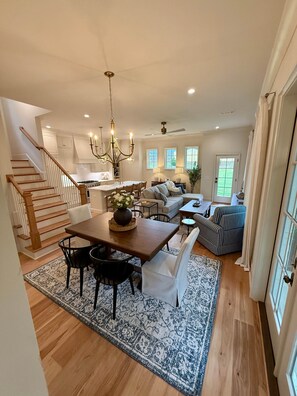 A spacious living area with a dining table, sofas, and a staircase.