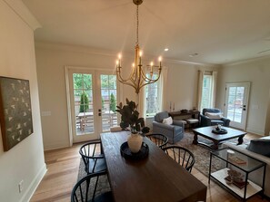 A spacious living area with a dining table, chairs, a sofa, and a chandelier. - King & Queen- King Unit II (Auburn)