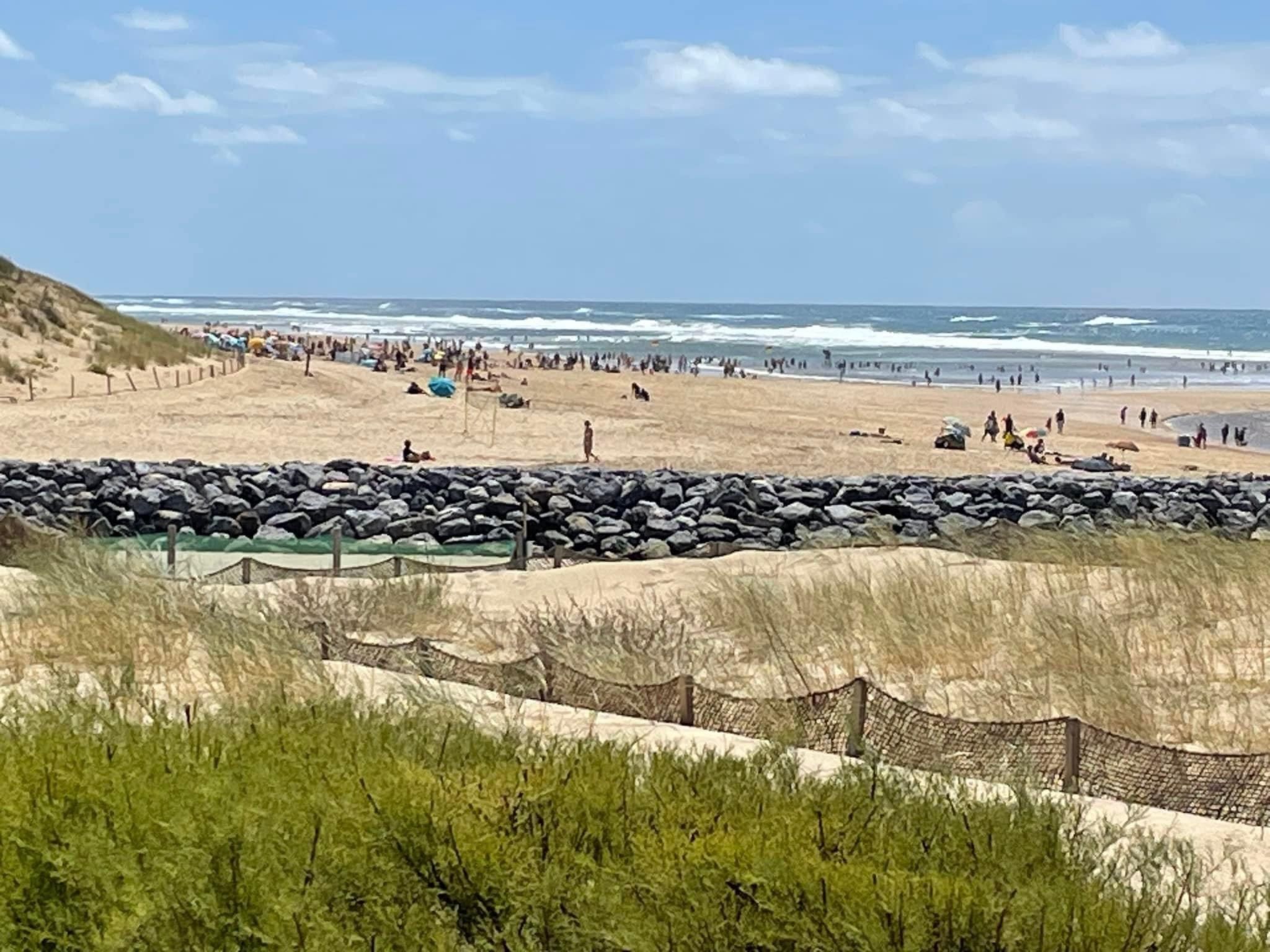 A beach with a rocky barrier and a grassy foreground.