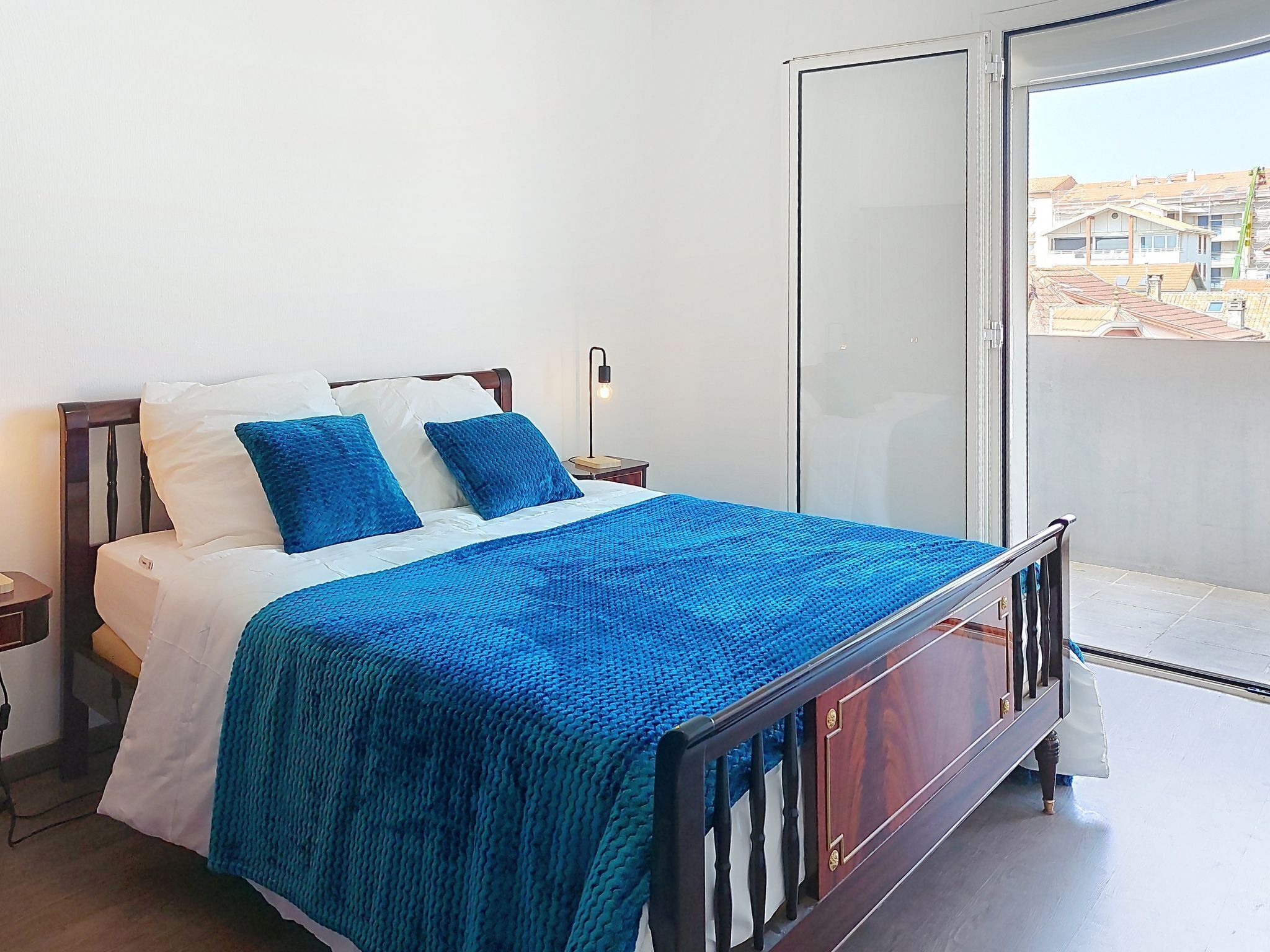 A bed with a blue blanket, white pillows, and a wooden headboard.