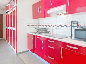 A kitchen with red cabinets, a microwave, and a kettle. - Les Dunes by Interhome (Mimizan)
