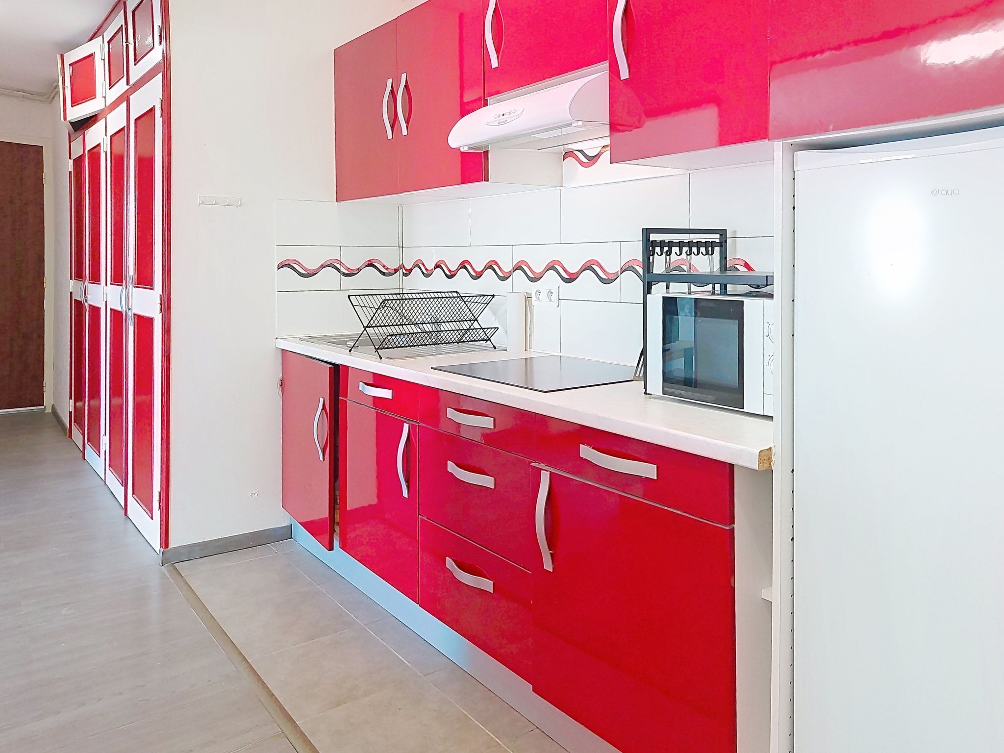 A kitchen with red cabinets, a microwave, and a sink.
