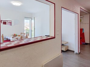 Ein Zimmer mit Esstisch, Stühlen, einem großen Spiegel, einer Heizung und einer Tür zu einem weiteren Raum.