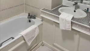 Un baño con bañera, ducha, lavamanos y espejo.