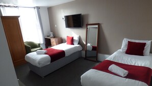 Habitación de hotel con dos camas, televisor, espejo, escritorio y una silla.