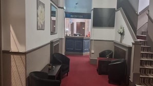Un hall de hotel con mostrador de recepción, zona de estar y una escalera.