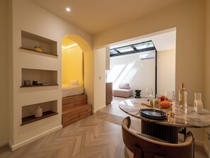 A modern hotel room with a wooden staircase, a dining area with a marble table, and a large mirror reflecting the room. - Atypical Studio Apartment - Cannes Californie (Cannes)