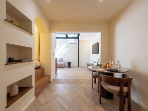 A modern interior with a dining area, wooden shelves, and a staircase leading to an upper level. - Atypical Studio Apartment - Cannes Californie (Cannes)