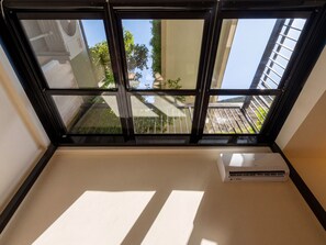 A room with a large window, an air conditioning unit, and a view of a balcony with greenery. - Atypical Studio Apartment - Cannes Californie (Cannes)