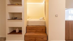 Eine Treppe führt zu einem Schlafzimmer mit einem Bett, Regalen und einem kleinen Tisch.