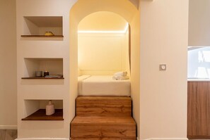 A staircase leading to a bedroom with a bed, shelves, and a small table. - Atypical Studio Apartment - Cannes Californie (Cannes)