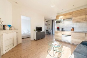 Ein modernes Wohnzimmer mit Kamin, Fernseher, Essbereich und Küche mit Holzschränken.