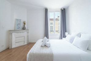 Ein Hotelzimmer mit Bett, Kamin, einem Vorhangfenster und Blick auf Gebäude.