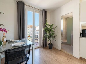 Ein modernes Apartment mit Balkon, einem Essbereich inklusive Tisch und Stühlen, einer Topfpflanze und Blick auf die Stadt.
