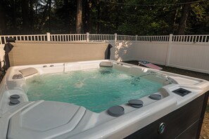 A hot tub with a control panel, surrounded by a white fence and trees. - Hot Tub-Game Room-Sun Room-Backyard-King-7 TVs-5 Bedrooms-4300 SqFt. Sleeps 12 (Honor)