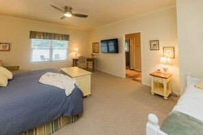 A bedroom with a bed, a desk, a chair, a television, and a door leading to another room. - Spacious 5-bedroom near Sleeping Bear Dunes/beaches - New Owner Special Pricing (Honor)