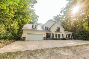 A two-story house with a garage, a stone foundation, and a brick driveway. - Hot Tub-Game Room-Sun Room-Backyard-King-7 TVs-5 Bedrooms-4300 SqFt. Sleeps 12 (Honor)