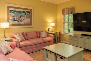 A living room with a sofa, a television, a painting, and a lamp. - Spacious 5-bedroom near Sleeping Bear Dunes/beaches - New Owner Special Pricing (Honor)