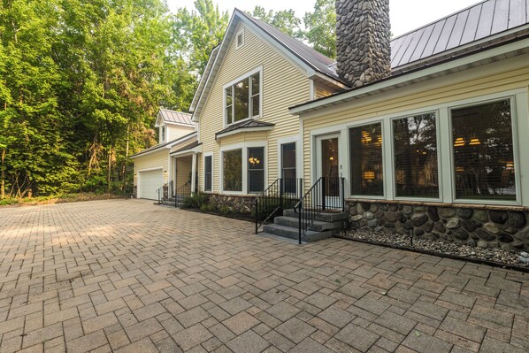 A two-story house with a stone foundation, a garage, and a paved driveway. - Hot Tub-Game Room-Sun Room-Backyard-King-7 TVs-5 Bedrooms-4300 SqFt. Sleeps 12 (Honor)