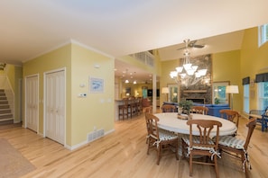 A spacious dining area with a round table and chairs, a chandelier, and a staircase leading to an upper level. - Hot Tub-Game Room-Sun Room-Backyard-King-7 TVs-5 Bedrooms-4300 SqFt. Sleeps 12 (Honor)