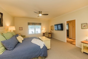 A bedroom with a bed, a desk, a chair, a television, and a door leading to another room. - Hot Tub-Game Room-Sun Room-Backyard-King-7 TVs-5 Bedrooms-4300 SqFt. Sleeps 12 (Honor)