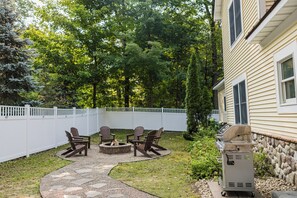 Ein Garten mit Feuerstelle, Gartenmöbeln und Grill.