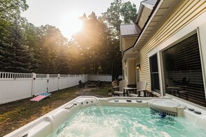 A backyard with a hot tub, outdoor seating, and a white fence. - Spacious 5-bedroom near Sleeping Bear Dunes/beaches - New Owner Special Pricing (Honor)