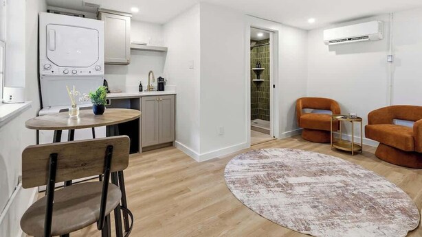 Een compacte leefruimte met een kitchenette, een eethoek en een zithoek met twee banken.