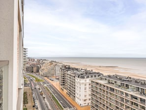 Ein Hochhaus mit mehreren Etagen, ein Strand im Hintergrund und eine Straße mit Fahrzeugen.