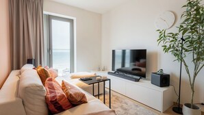 Een moderne woonkamer met een bank, televisie en een potplant.