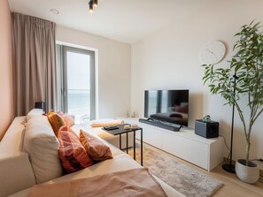 A modern living room with a sofa, television, and a potted plant. - O'Sea with seaview & terrace by Interhome (Oostende)