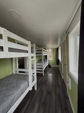 A narrow corridor with bunk beds, a window, and a door.