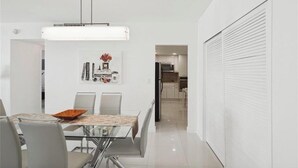 Et moderne spiseområde med et glasbord, stole og en hængende lampe.