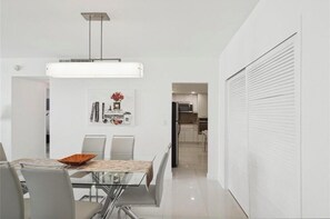 A modern dining area with a glass table, chairs, and a pendant light. - Luxury Beach Front View and Comfort Best line in the building, direct ocean view (Hollywood)