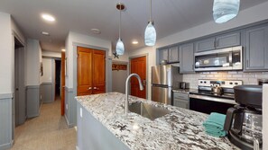 A modern kitchen with granite countertops, stainless steel appliances, and pendant lighting. - Cozy 1-bedroom 250 Rimfire Lodge in the serene SnowShoe Village Western Sunset (Slaty Fork)
