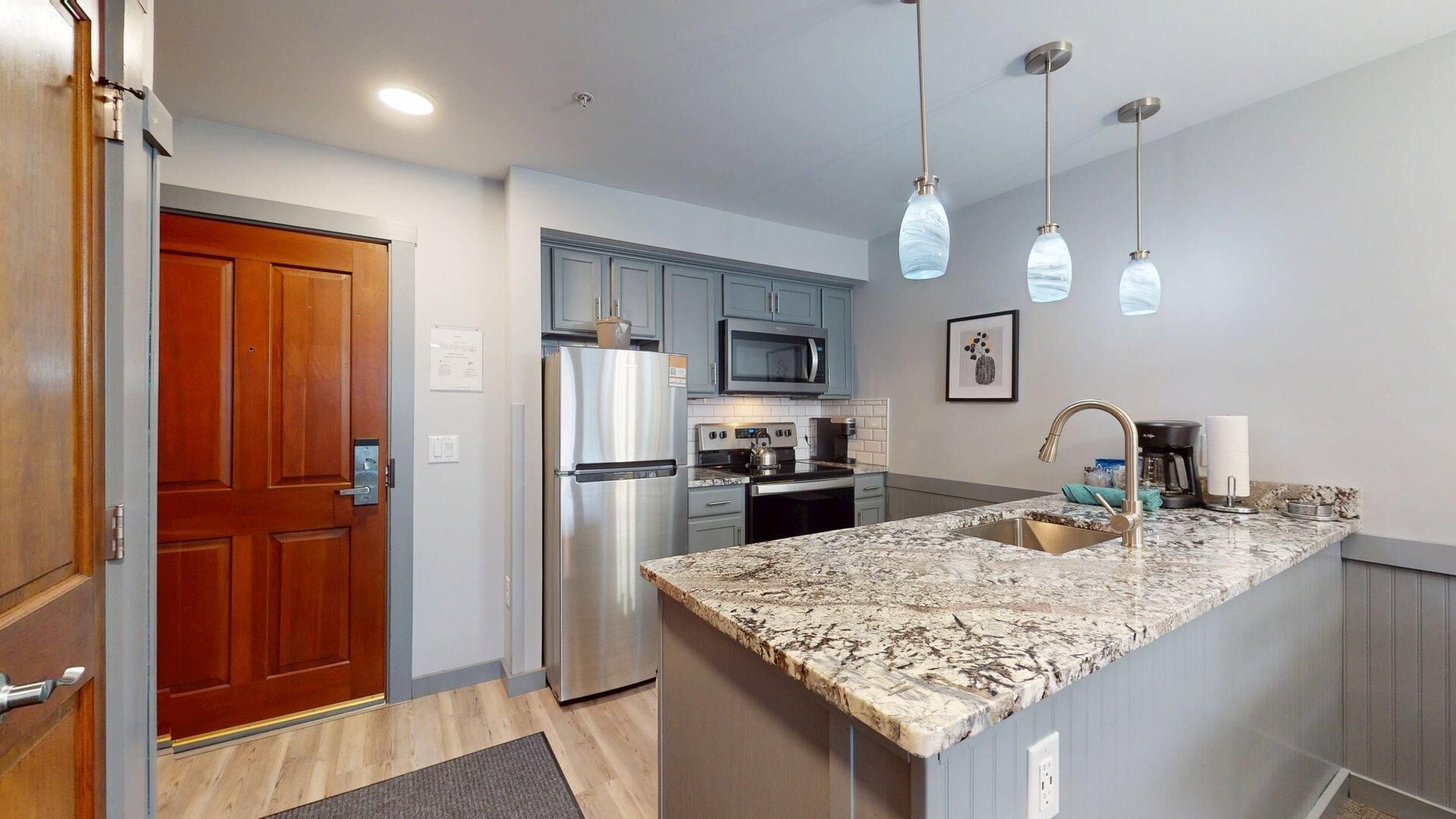 A modern kitchen with granite countertops, stainless steel appliances, and pendant lighting.