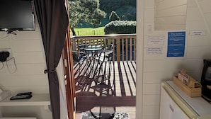 Una stanza con televisore, scrivania, computer, finestra con tende e vista su un patio con mobili da esterno.