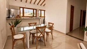 A modern kitchen with a glass dining table, wooden chairs, and a view of the mountains through large windows.