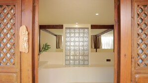 A traditional wooden door with a lattice design, a room with a white wall, a glass partition, and a plant. - BX Star River Hotel (Lijiang)