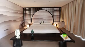 A hotel room with a bed, a nightstand, a decorative wall, and a curtain. - BX Star River Hotel (Lijiang)