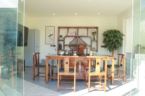 Ein Essbereich mit Holztisch und -stühlen, einer dekorativen Holzvertäfelung mit Regalen, einem Kühlschrank und einer Topfpflanze.