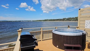 Een terras met een hottub, een barbecue en uitzicht op het meer.